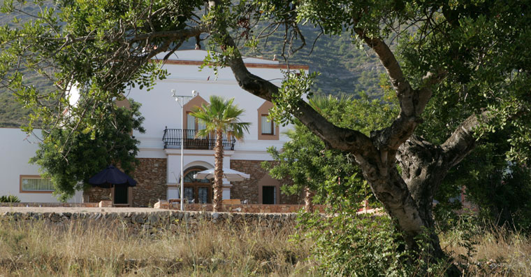 Fachada de la masía entre algarrobos