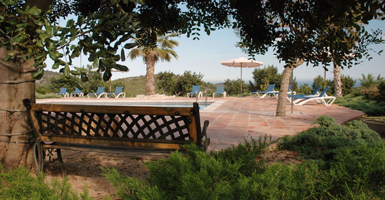 Rincón del jardín con banco frente a la piscina